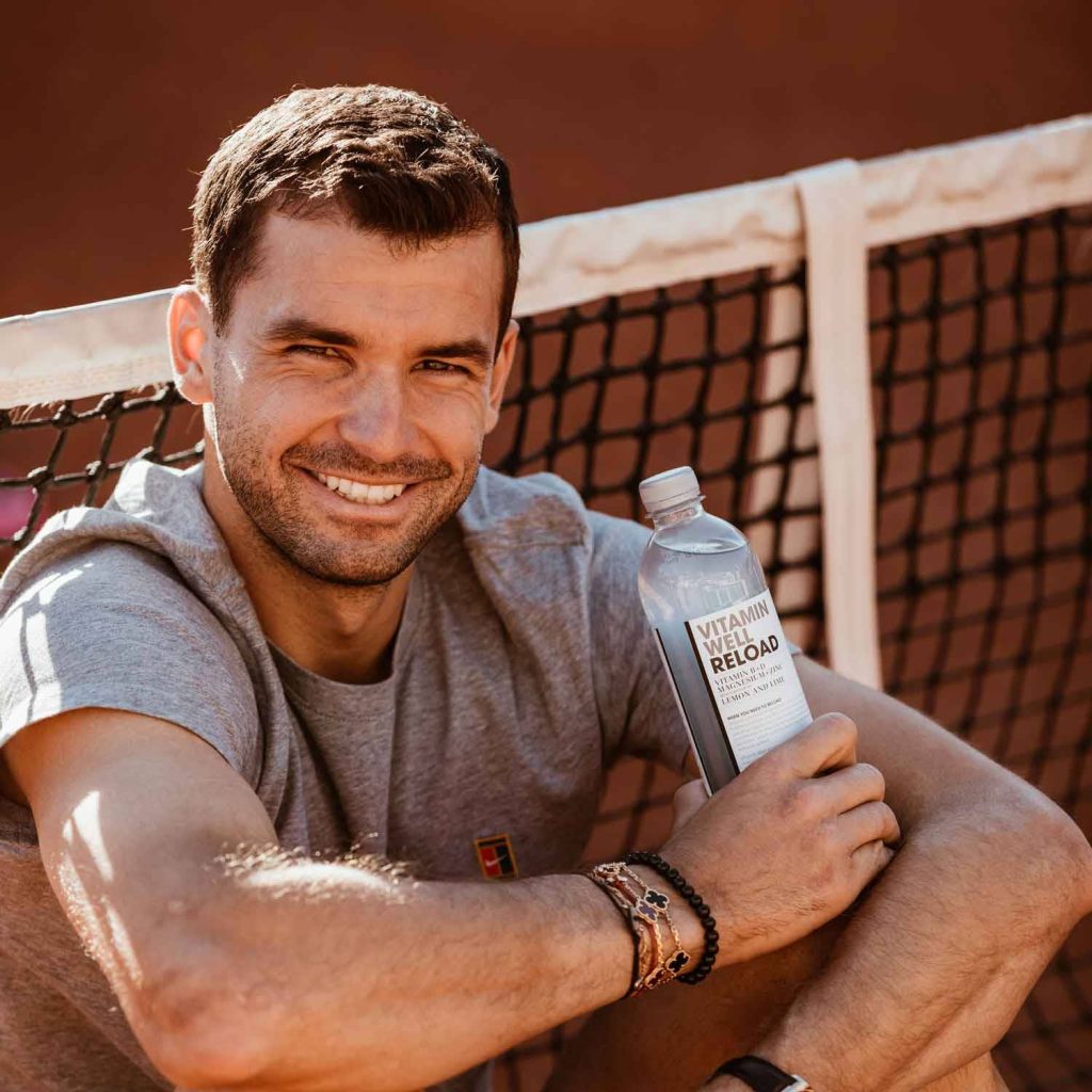 Grigor Dimitrov tennis player sitting on clay court holding Vitamin Well Reload bottle smiling Wallpaper