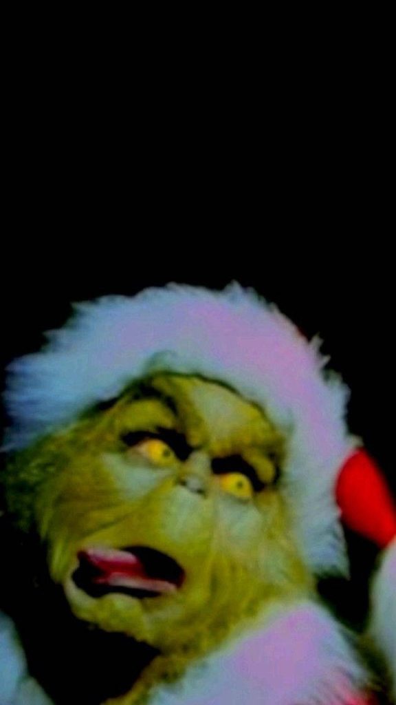 Grinch live-action 2000 movie wallpaper Grinch in Santa hat sticking tongue out festive background