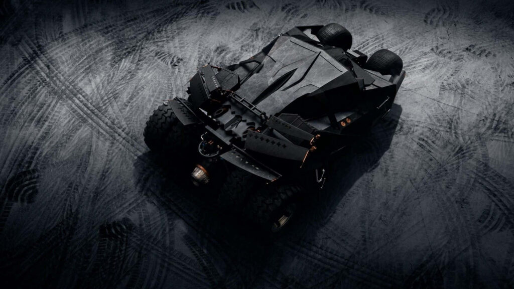 Batmobile Enveloped in Menacing Metal, Impressive Wheels, and its Mighty Trail across the Gravelly Terrain Wallpaper