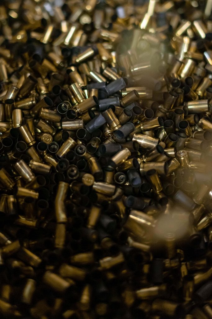 Close-up of spent brass shell casings pile with moody lighting and shallow depth for texture wallpaper