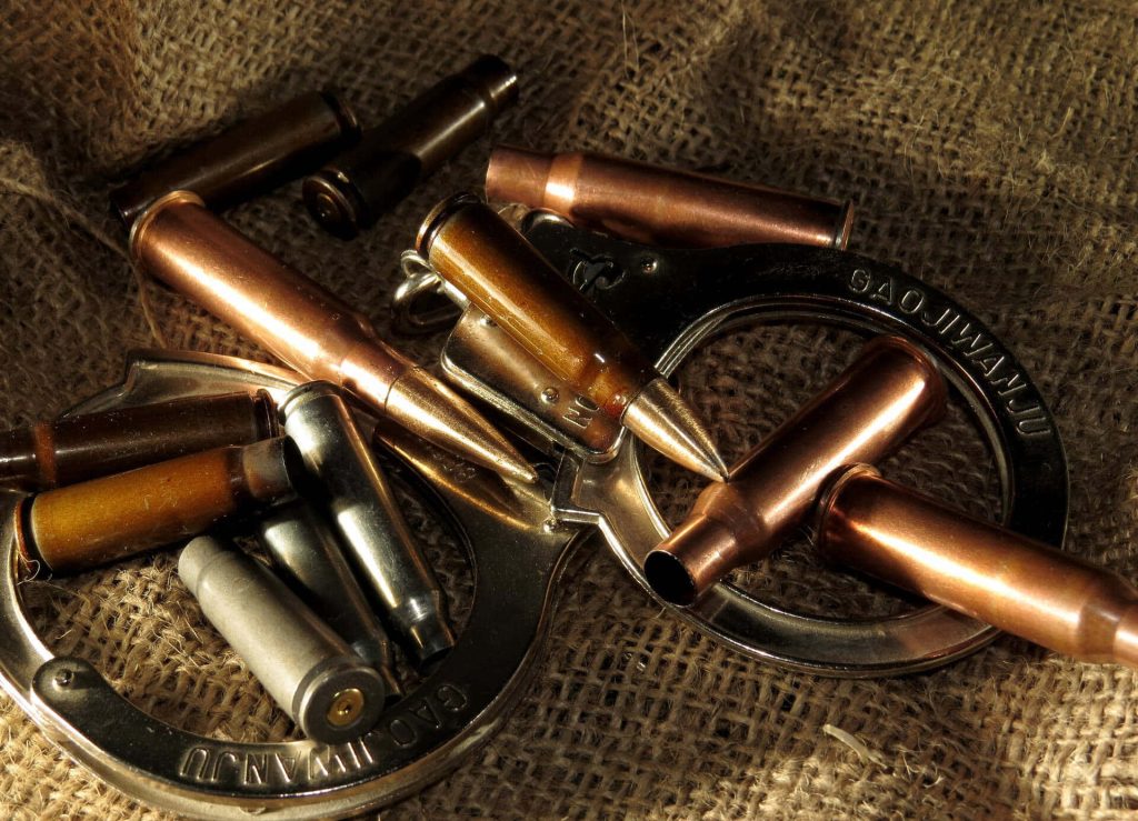 Close-up of metallic rifle cartridges on steel Gaojiwanju handcuffs with burlap background Wallpaper