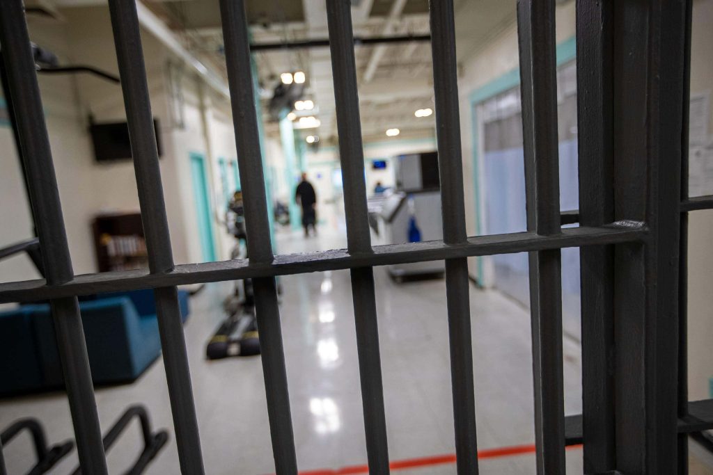 Prison corridor view through dark metal bars gritty jail wallpaper with somber restricted atmosphere