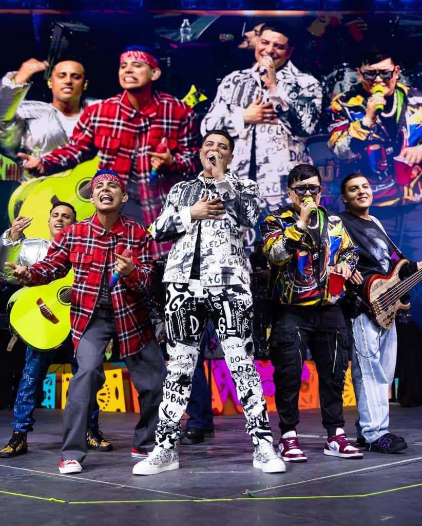 Grupo Firme live concert featuring lead singer Eduin Caz in stylish suit vibrant stage wallpaper