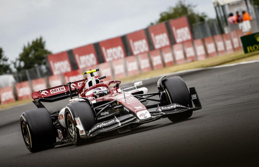 Guanyu Zhou racing red and black Formula 1 car on track dynamic motorsport wallpaper background