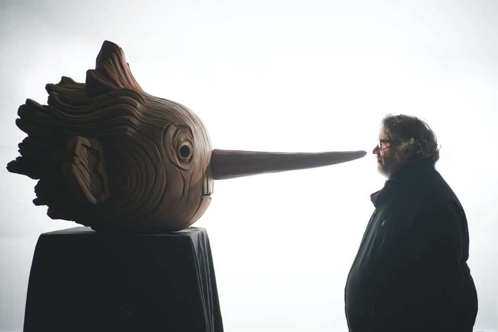 Filmmaker Guillermo del Toro faces giant carved wooden Pinocchio head cinematic silhouette wallpaper