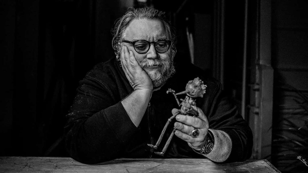 Guillermo del Toro with hand-crafted wooden Pinocchio puppet cinematic black and white wallpaper