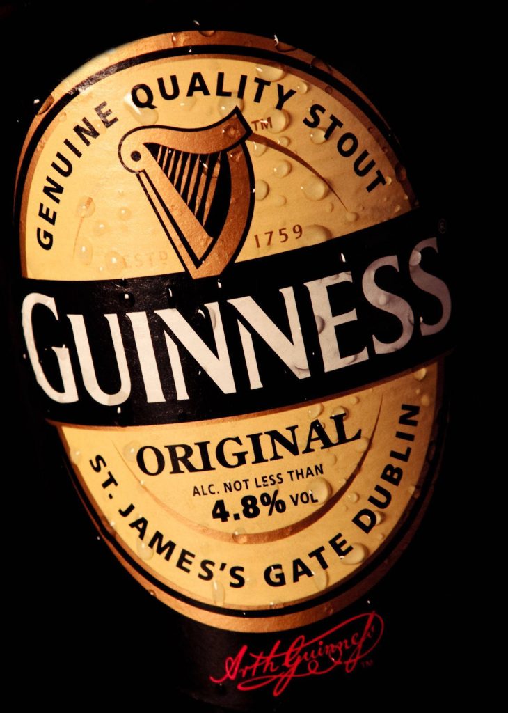 Close-up of chilled Guinness Original Irish Dry Stout bottle with condensation and harp logo Wallpaper