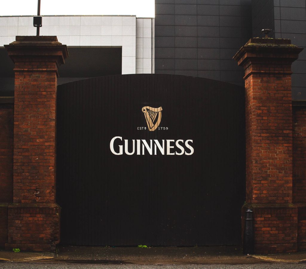 Guinness St James's Gate black gate with white harp logo and red brick pillars background wallpaper