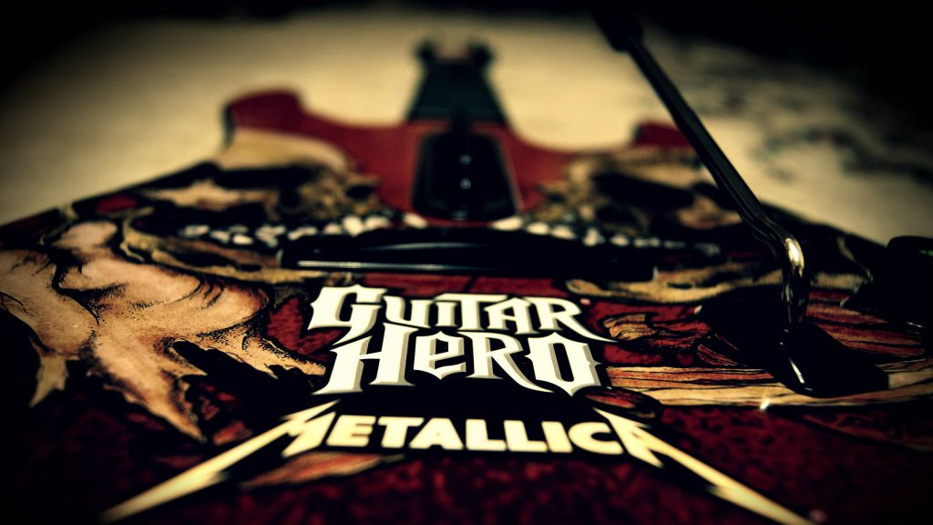 Close-up of Guitar Hero Metallica guitar controller with logos on textured red background Wallpaper