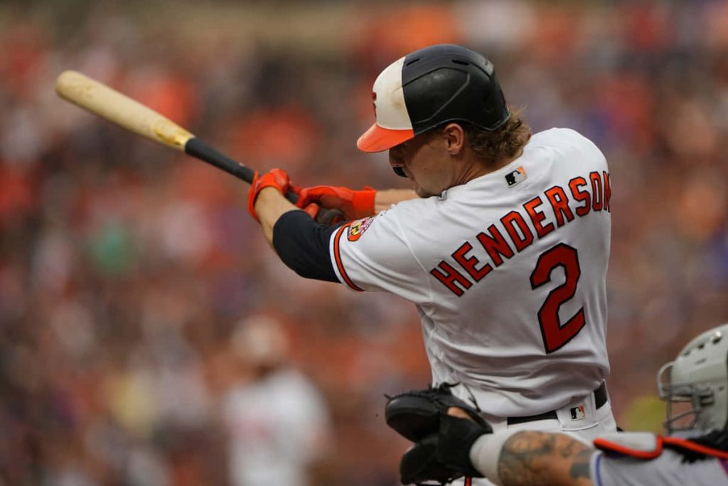 Baltimore Orioles Gunnar Henderson swinging bat in white jersey number 2 stadium backdrop Wallpaper