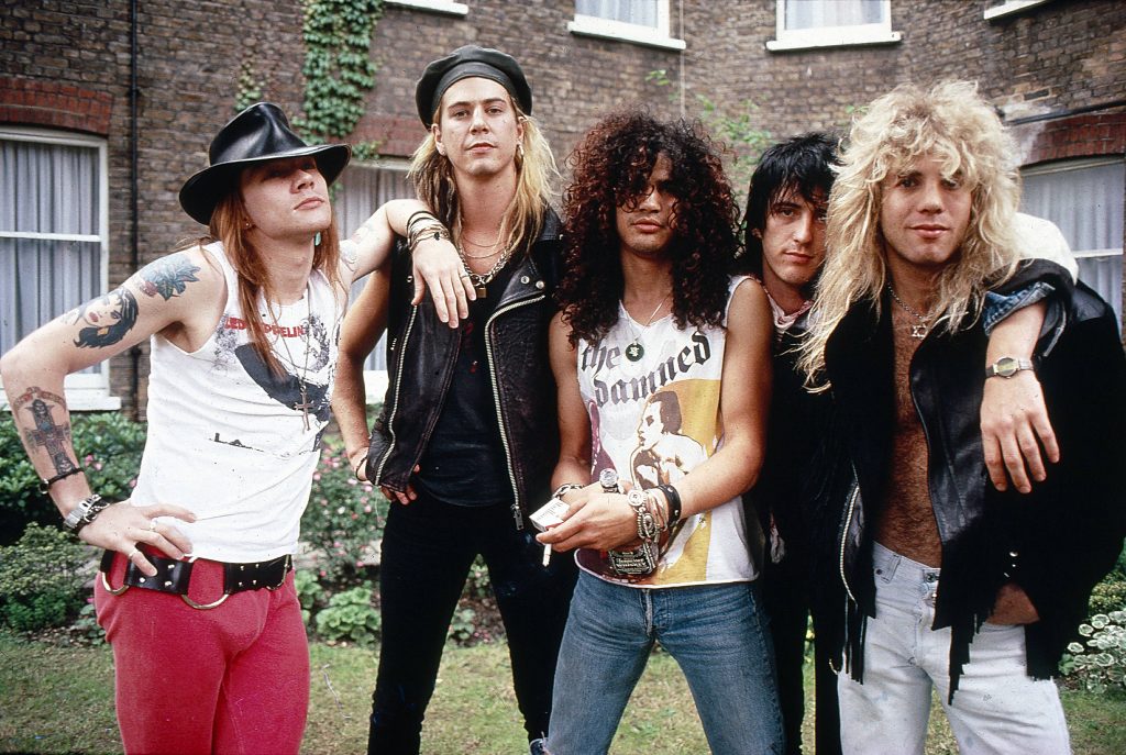 Guns N' Roses 1987 band portrait with Axl Rose, Slash, and members on gritty brick wall background Wallpaper