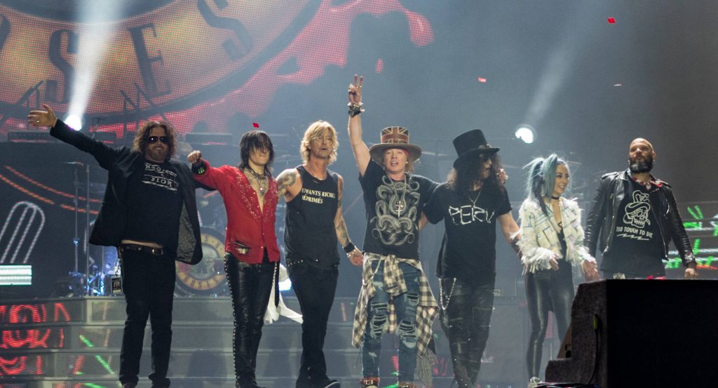 Guns N' Roses band taking a bow on stage with vibrant lights and confetti background wallpaper