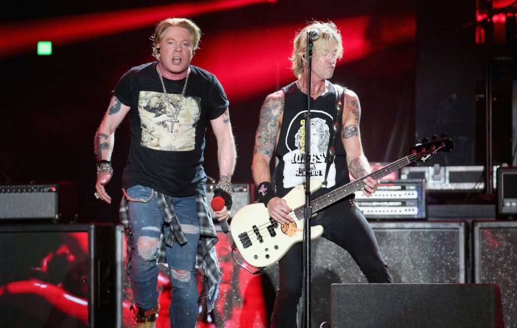 High-energy live concert photo of Guns N Roses Axl Rose and Duff McKagan in red lighting Wallpaper