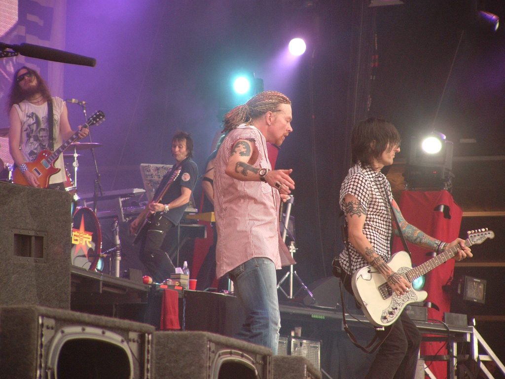Guns N Roses live concert with Axl Rose and guitarists vibrant stage lighting rock wallpaper