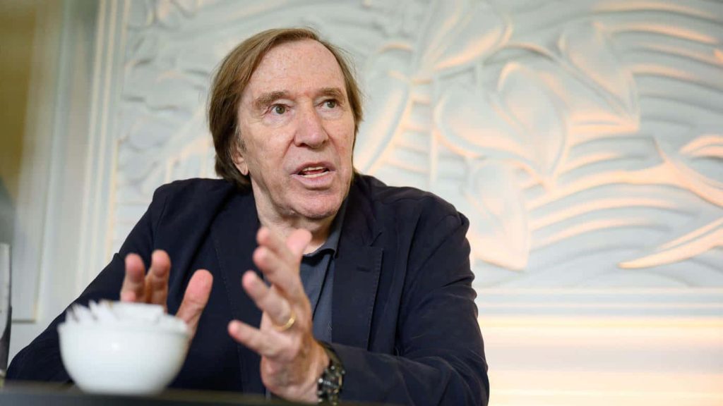 Günter Netzer football legend in dark blazer candid portrait bright textured background wallpaper