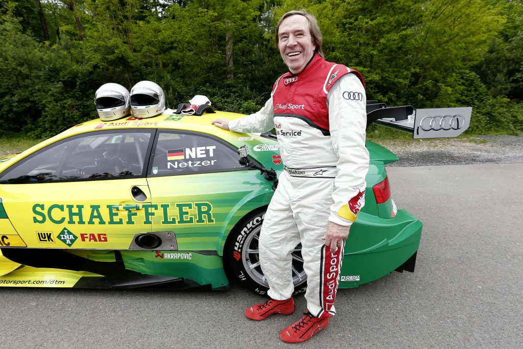 Günter Netzer in racing suit beside green yellow Audi DTM car forest background high resolution Wallpaper