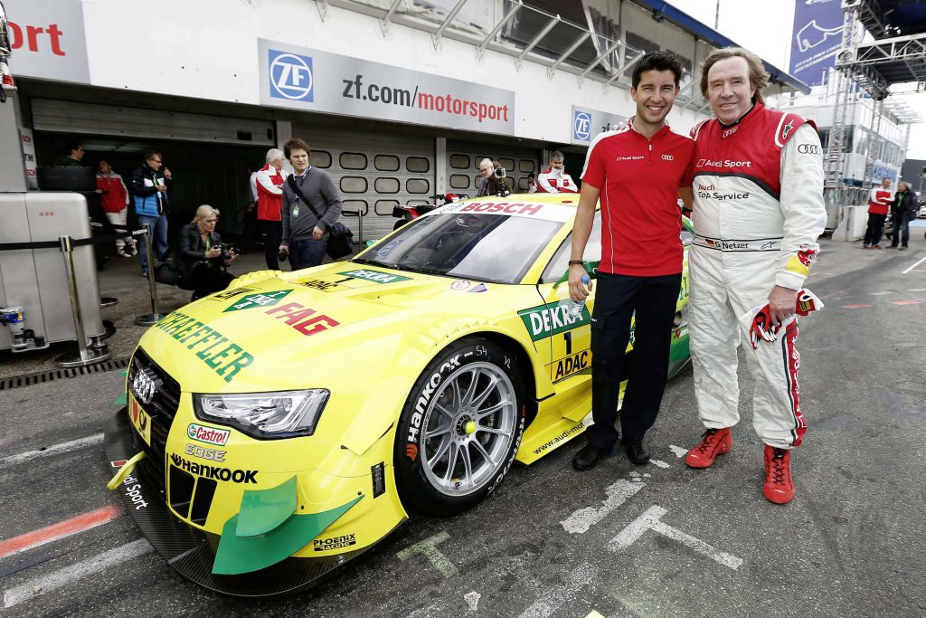 Günter Netzer with yellow Audi DTM race car in pit lane vibrant Audi Sport motorsport scene Wallpaper