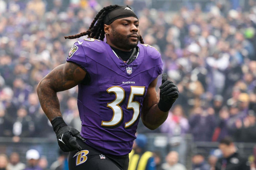 Gus Edwards Baltimore Ravens running back number 35 in action blurred stadium background wallpaper