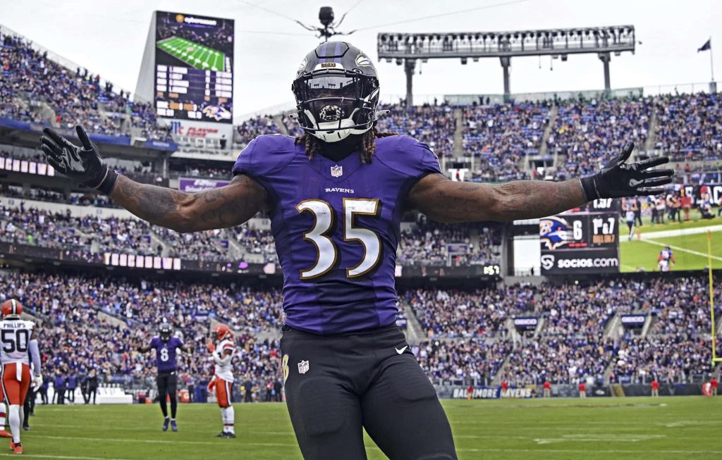 Baltimore Ravens Gus Edwards celebrating on field in purple jersey NFL wallpaper background