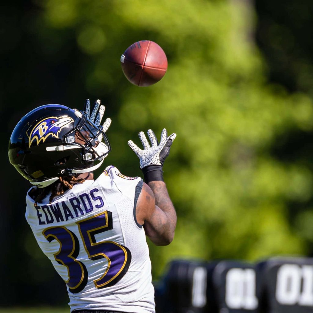 Baltimore Ravens Gus Edwards number 35 catching football in focused NFL practice session outdoors Wallpaper