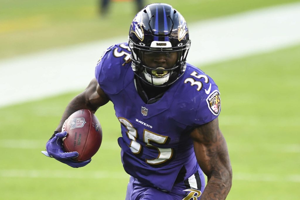 Baltimore Ravens Gus Edwards running back mid-play in purple jersey NFL action wallpaper