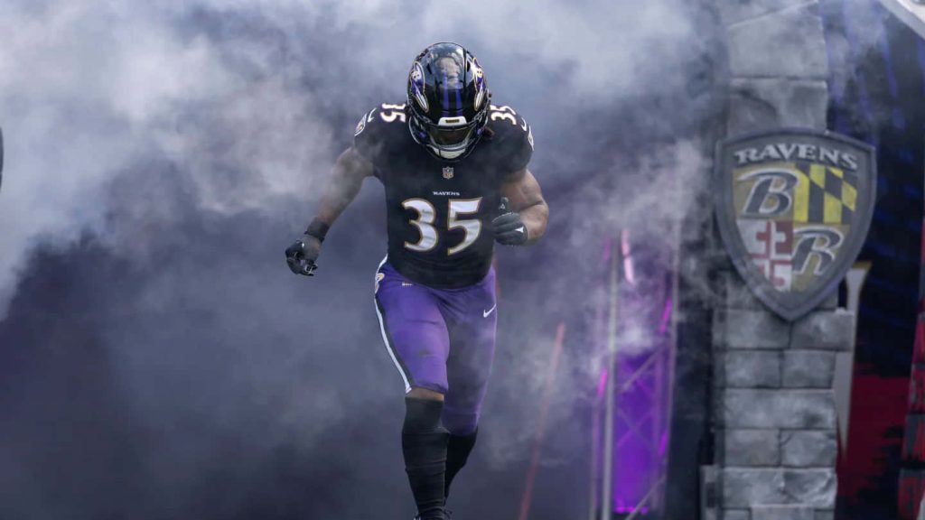 Baltimore Ravens Gus Edwards #35 running back bursts through stadium smoke by team shield wallpaper