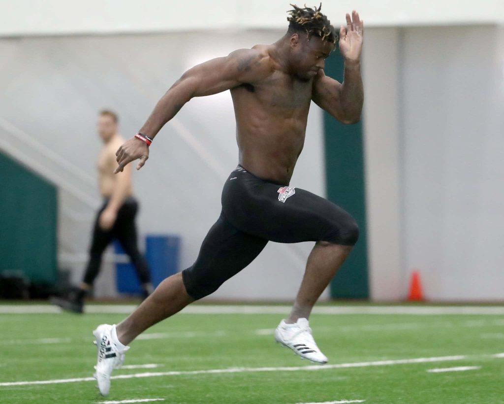 Gus Edwards sprinting powerfully on indoor turf in black gear and white cleats high intensity Wallpaper