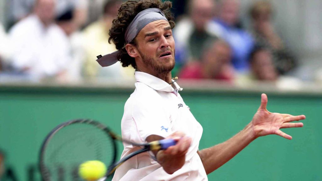 Brazilian tennis legend Gustavo Kuerten hitting forehand with motion blur on tournament court wallpaper