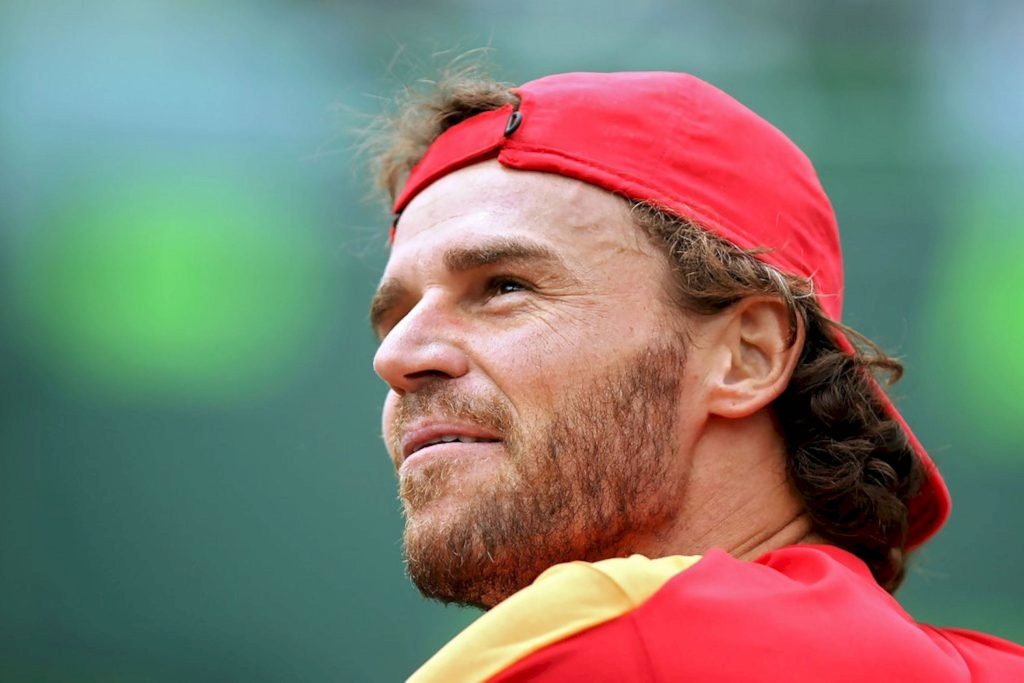 Tennis icon Gustavo Kuerten in red cap side portrait with focused gaze green background wallpaper