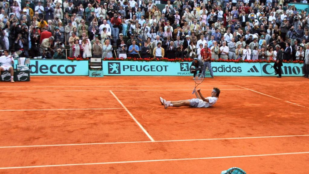 Gustavo Kuerten celebrates victory on Roland Garros red clay court in vibrant tennis action Wallpaper