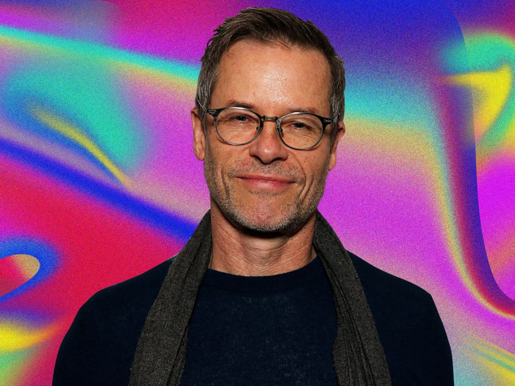 Portrait of Guy Pearce with glasses and scarf against neon purple pink blue psychedelic background Wallpaper