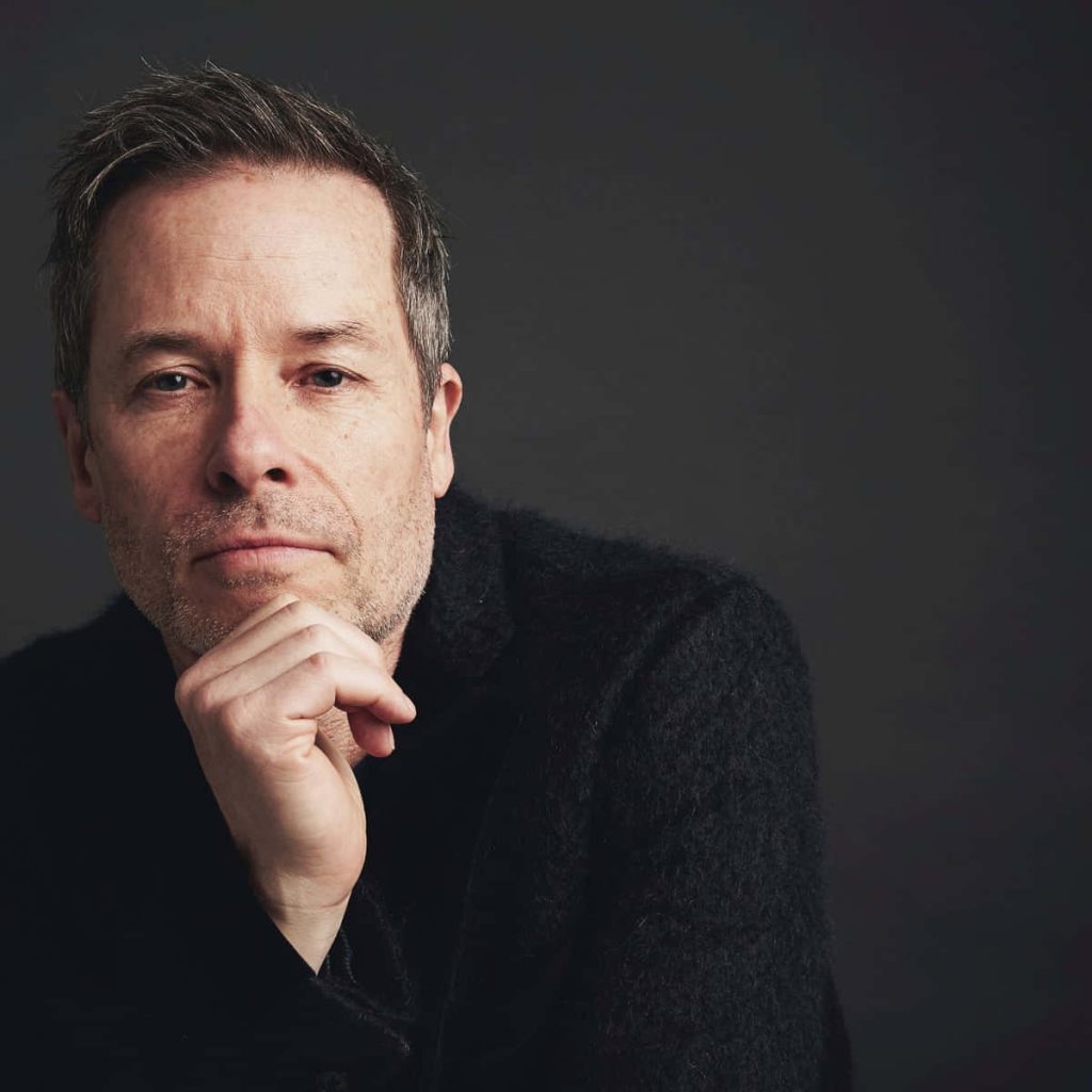 Studio portrait of actor Guy Pearce thoughtful pose dark minimalist background dramatic lighting wallpaper