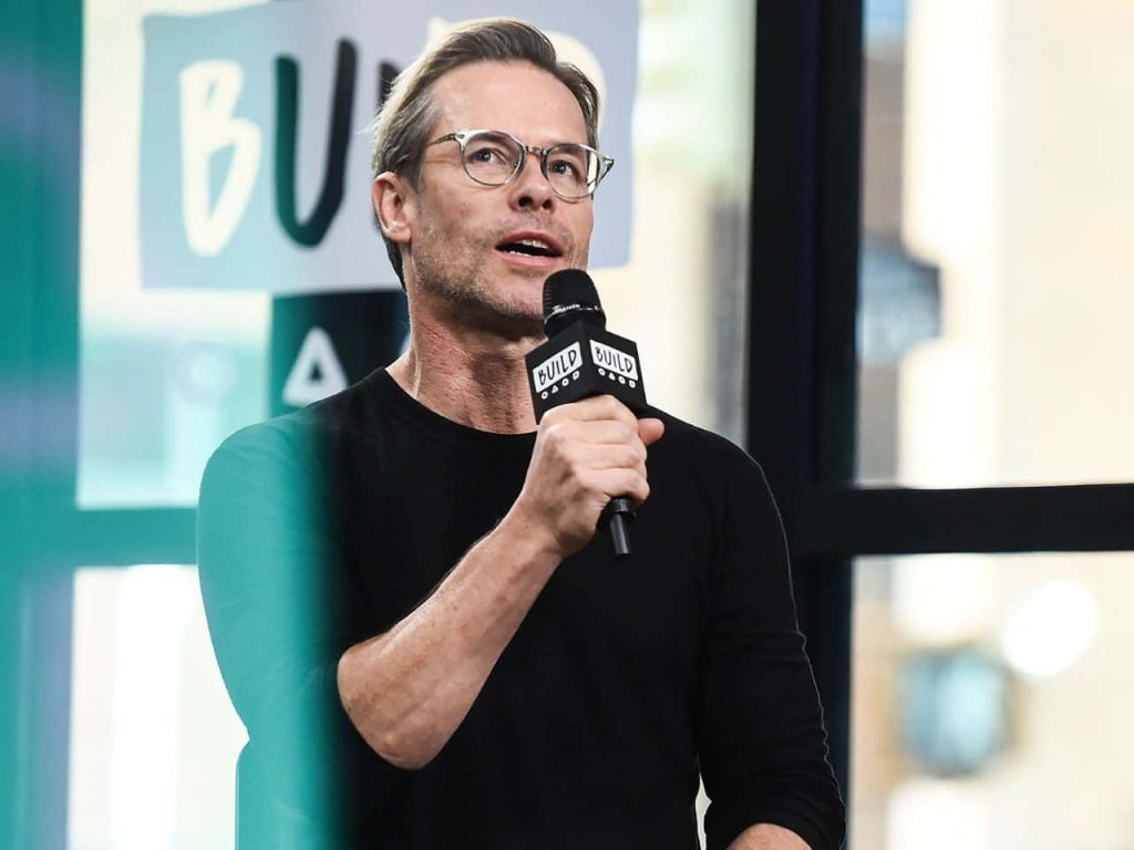 Guy Pearce in black sweater and glasses speaking during Build Series interview studio backdrop wallpaper