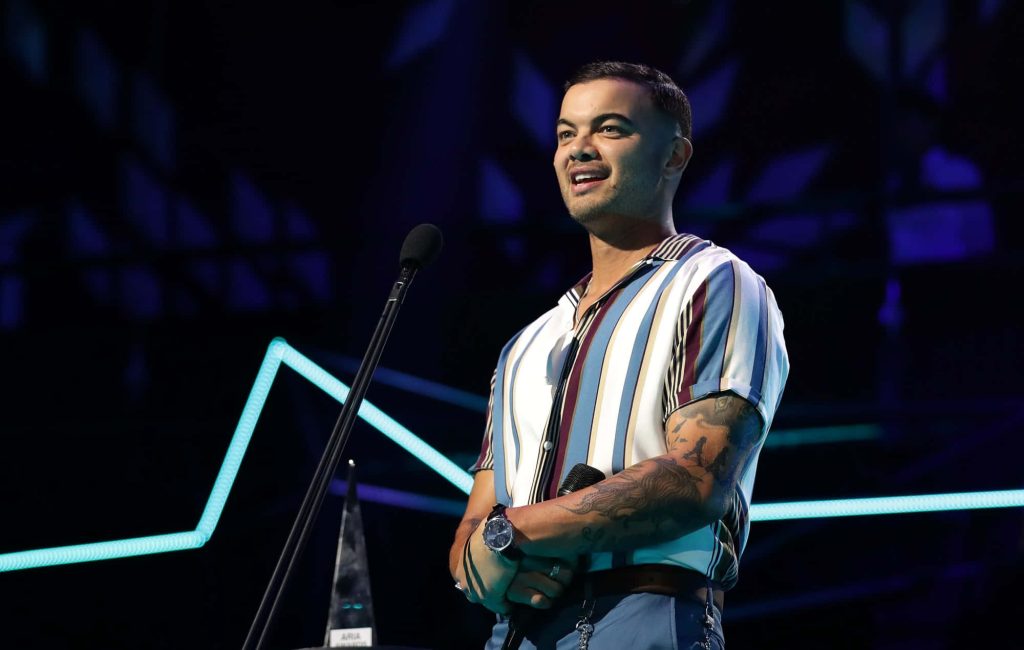 Guy Sebastian performing live at ARIA Awards with blue neon lights and visible tattoos wallpaper
