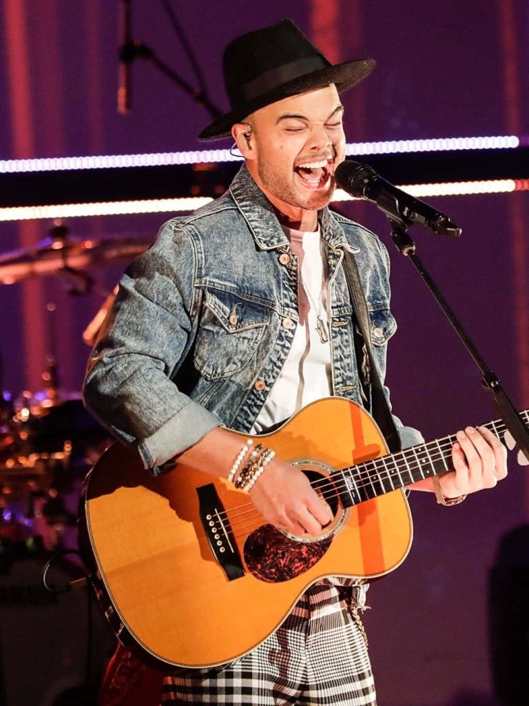 Guy Sebastian performing live with acoustic guitar in denim jacket and fedora on stage lights Wallpaper