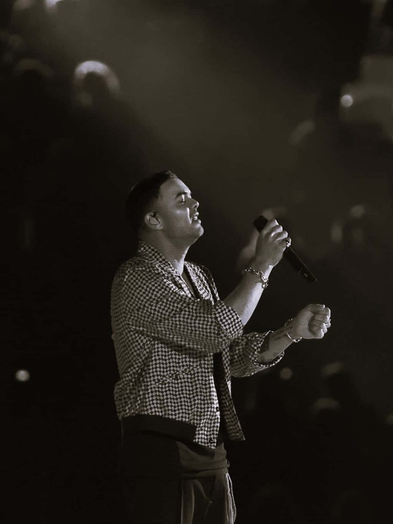 Guy Sebastian singing passionately in checkered shirt black and white concert wallpaper background