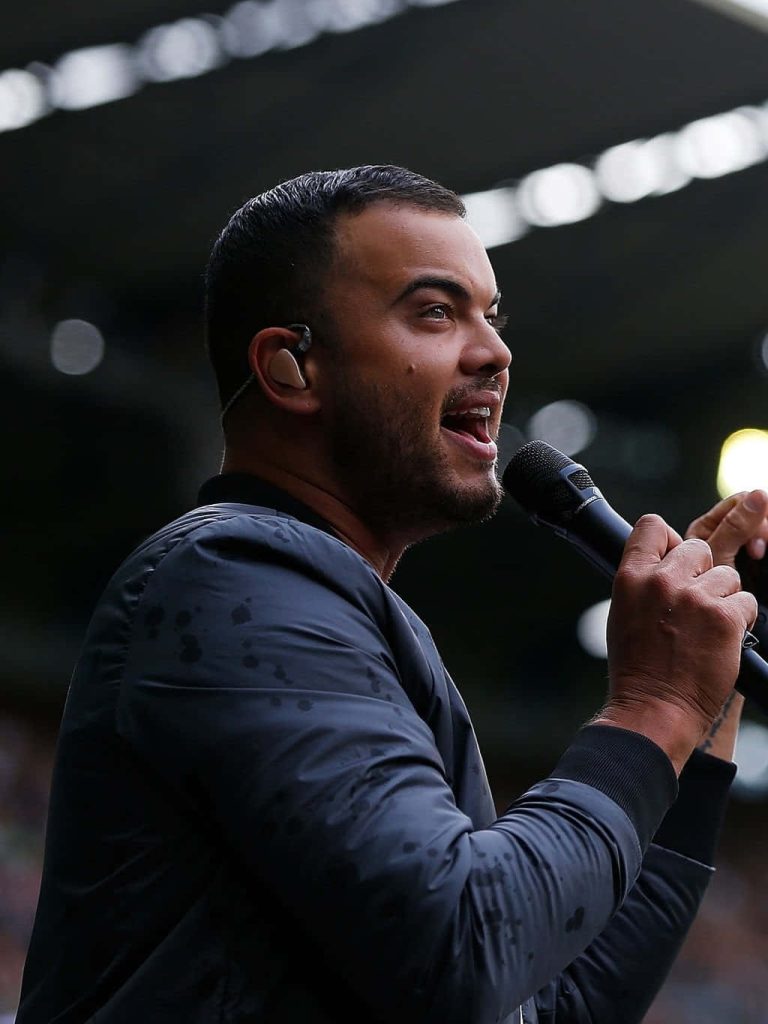 Australian singer Guy Sebastian performing live passionately with microphone and stage lighting Wallpaper