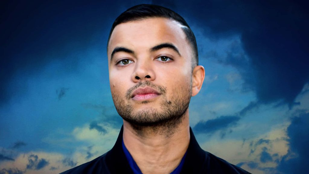 Australian singer Guy Sebastian intense gaze close-up with stormy blue sky wallpaper background