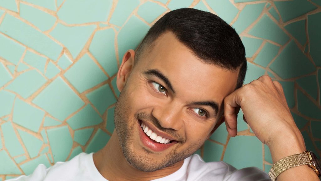 Guy Sebastian smiling studio portrait white t-shirt gold watch vibrant mint green mosaic background Wallpaper