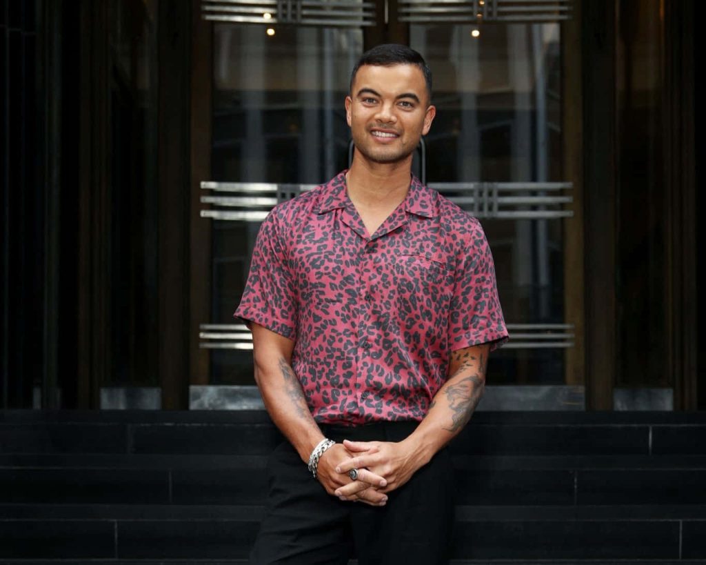 Guy Sebastian smiling in red leopard shirt with dark modern backdrop stylish wallpaper image