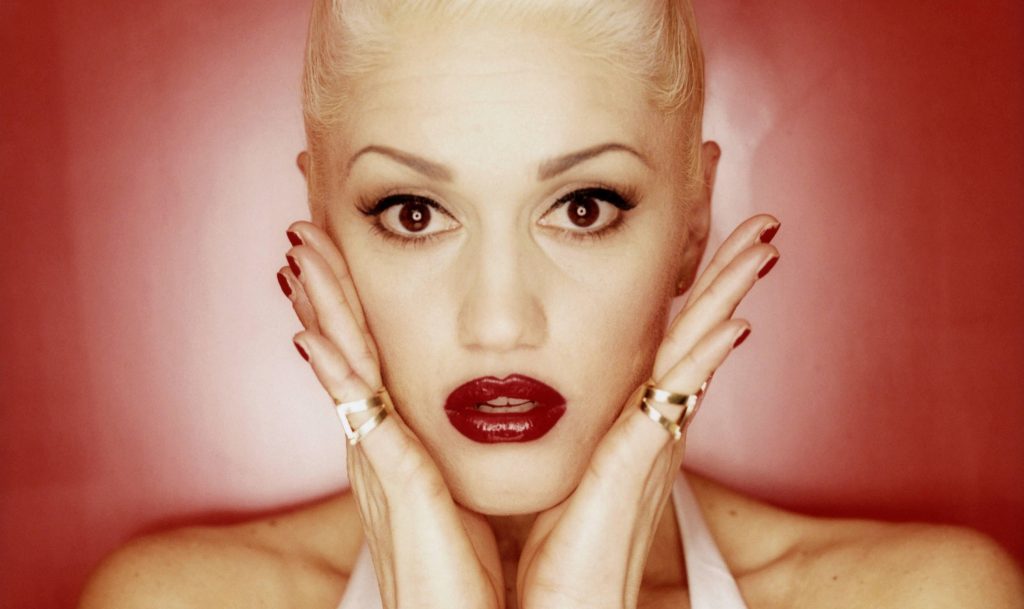 Gwen Stefani portrait wallpaper with bold red lips gold rings and vibrant red background HD