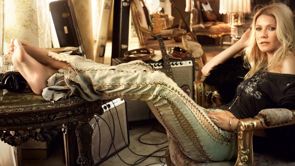 Gwyneth Paltrow in laced pants and Angels t-shirt lounges with guitars warm lighting editorial Wallpaper