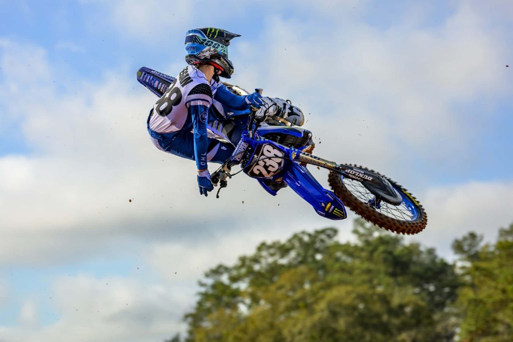 Motocross pro Haiden Deegan jumps high on Yamaha 238 bike against bright sky background Wallpaper