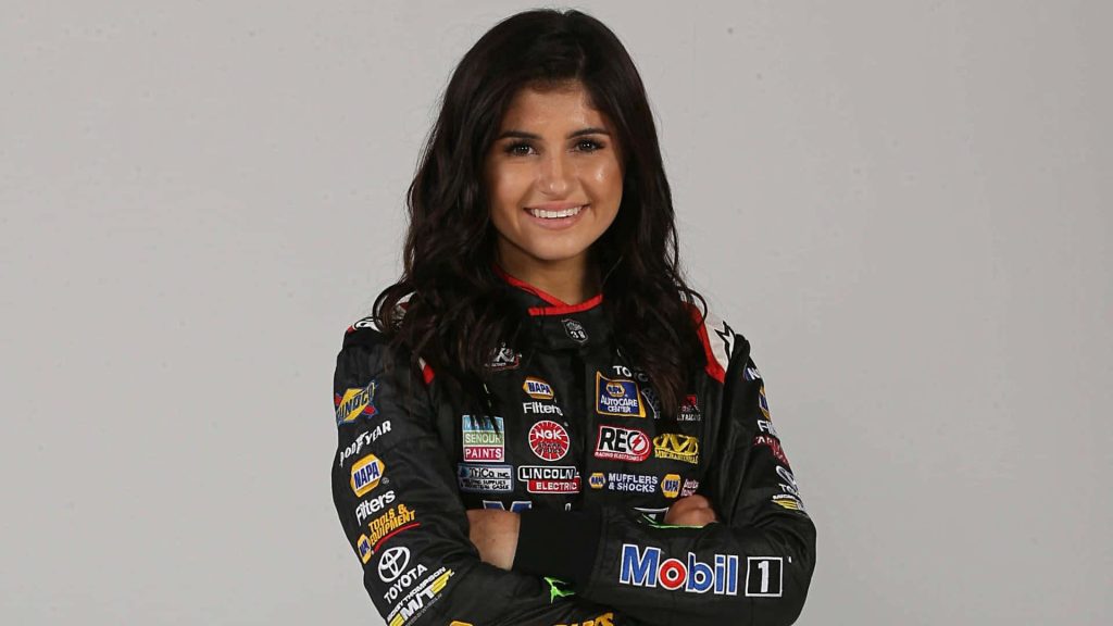 Race car driver Hailie Deegan smiling in black Toyota NAPA Mobil 1 racing suit studio portrait Wallpaper
