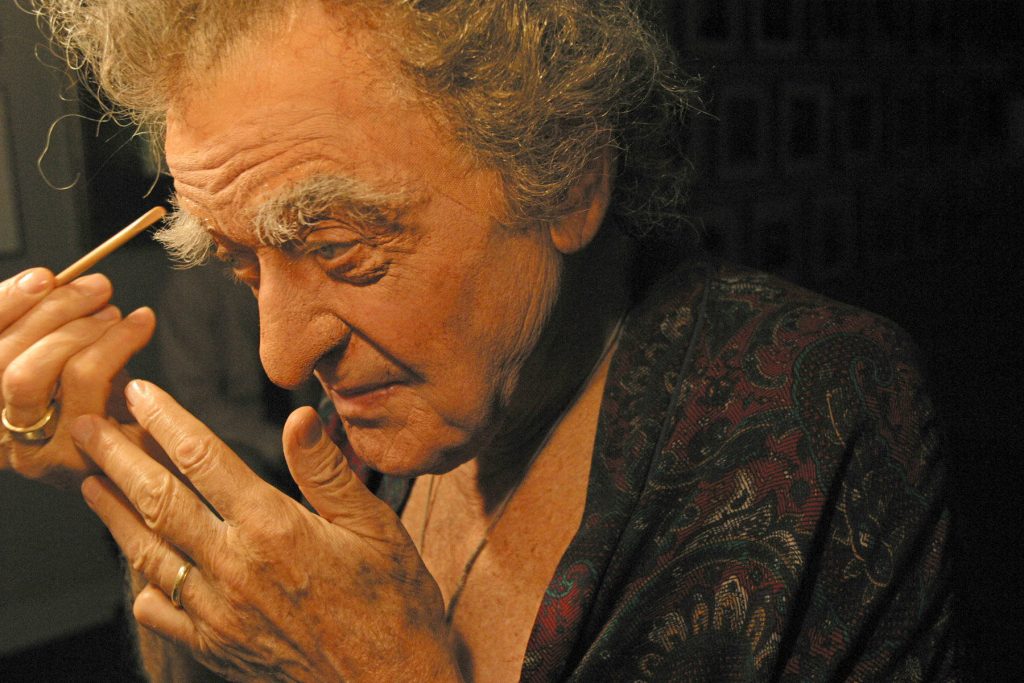 Hal Holbrook focused applying makeup in dark robe soft warm light artistic portrait background Wallpaper