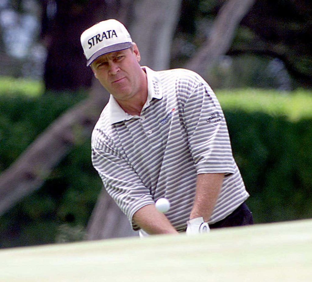 Professional golfer Hal Sutton focused mid-swing in Strata hat striped polo on green course Wallpaper