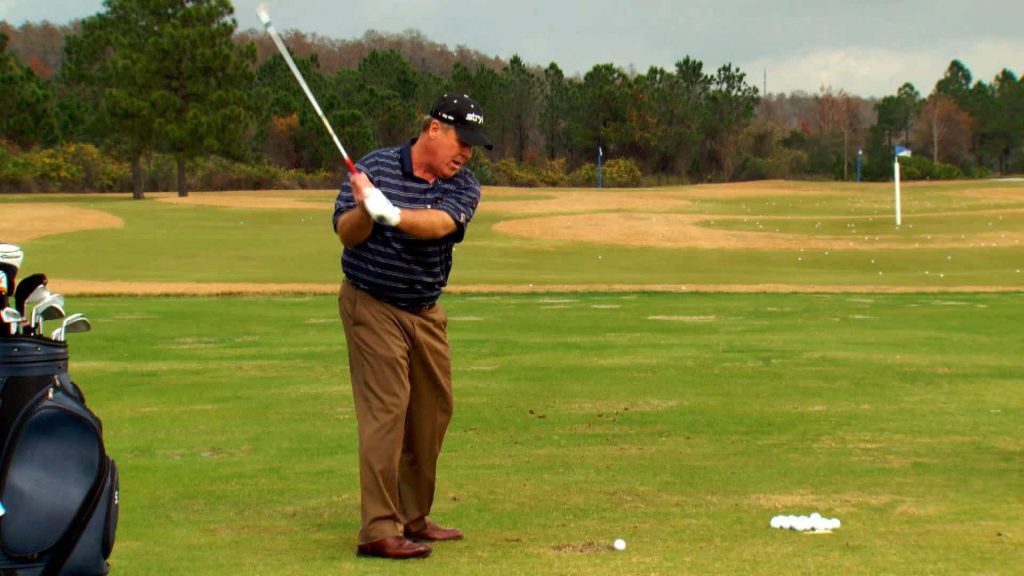 Hal Sutton focused golf swing on practice range with classic golf bag and balls background Wallpaper