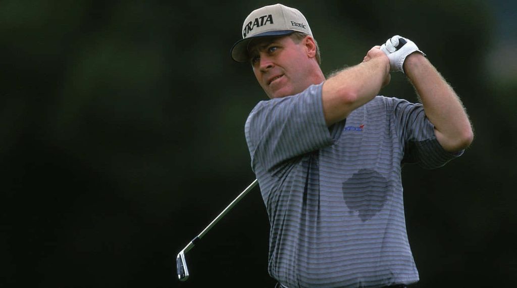 Professional golfer Hal Sutton mid-swing in striped polo dark background golf wallpaper background
