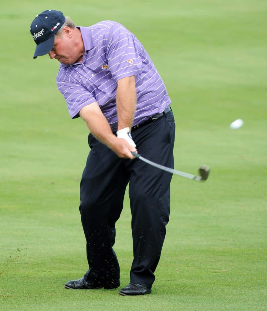 Hal Sutton golf swing on lush fairway in purple striped polo expert form precision action Wallpaper