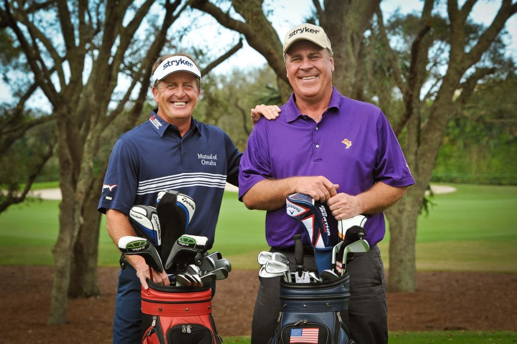 Professional golfers Hal Sutton and Fred Funk smiling on sunny golf course with bags Wallpaper